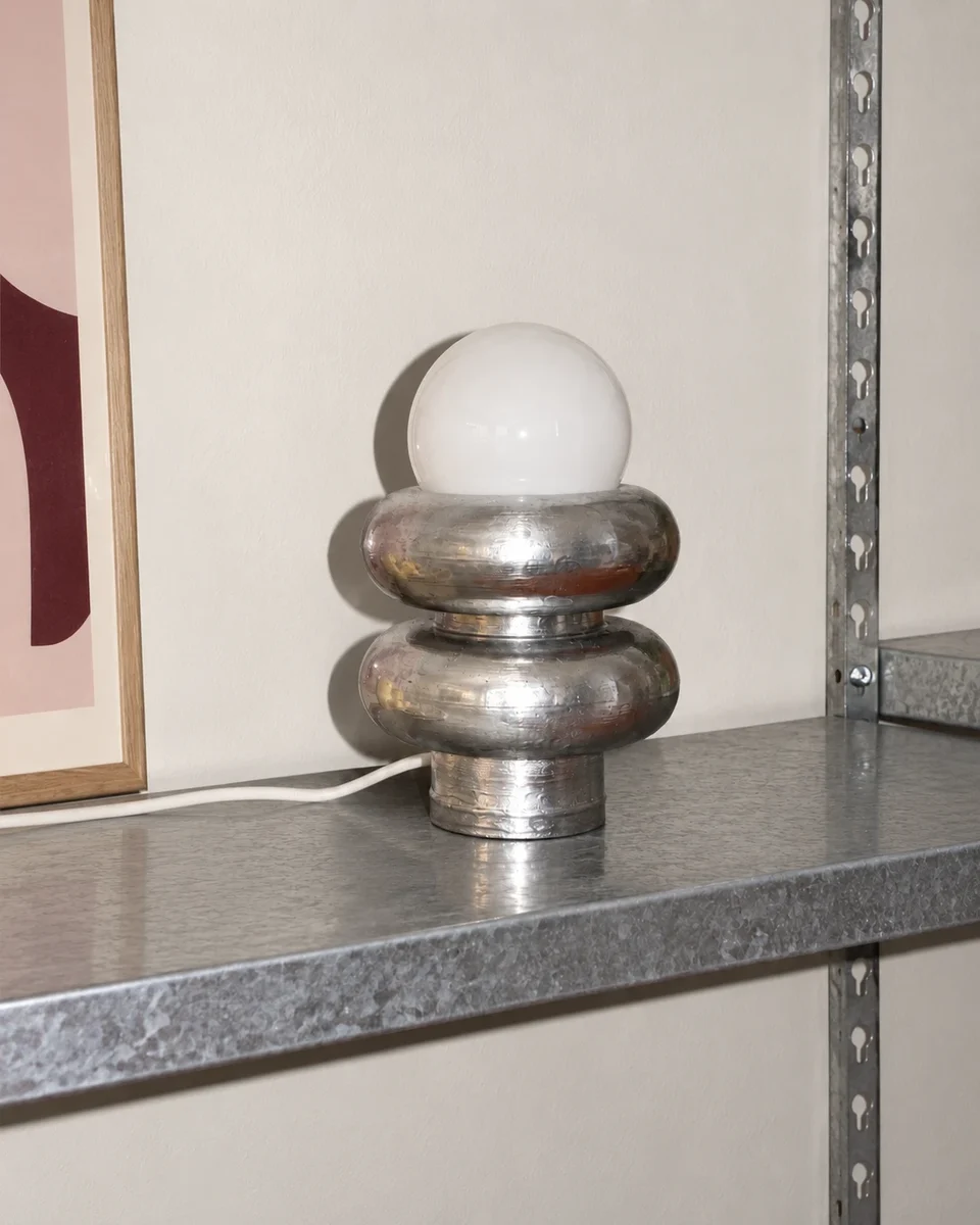 Guada's chrome lamp with a frosted globe on a steel shelf